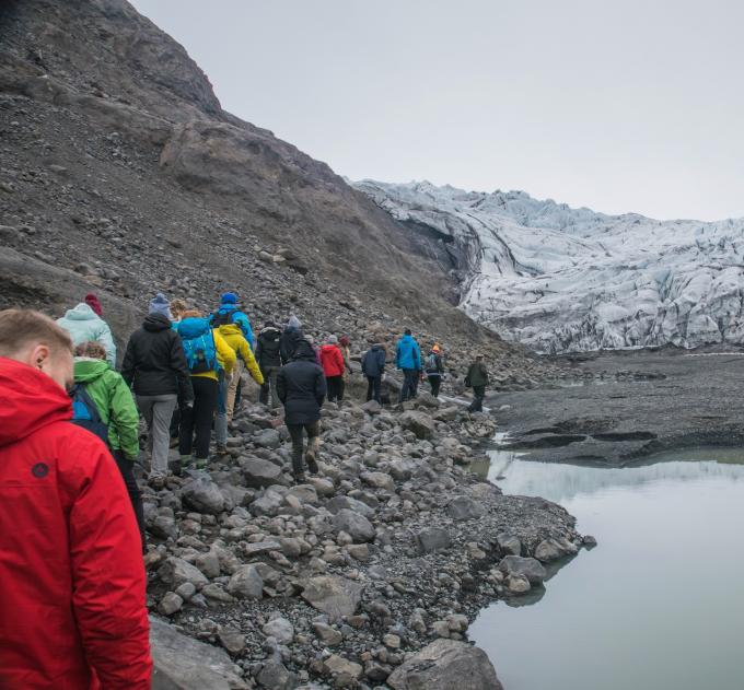 Students walking along a rocky path in Iceland among mountains.